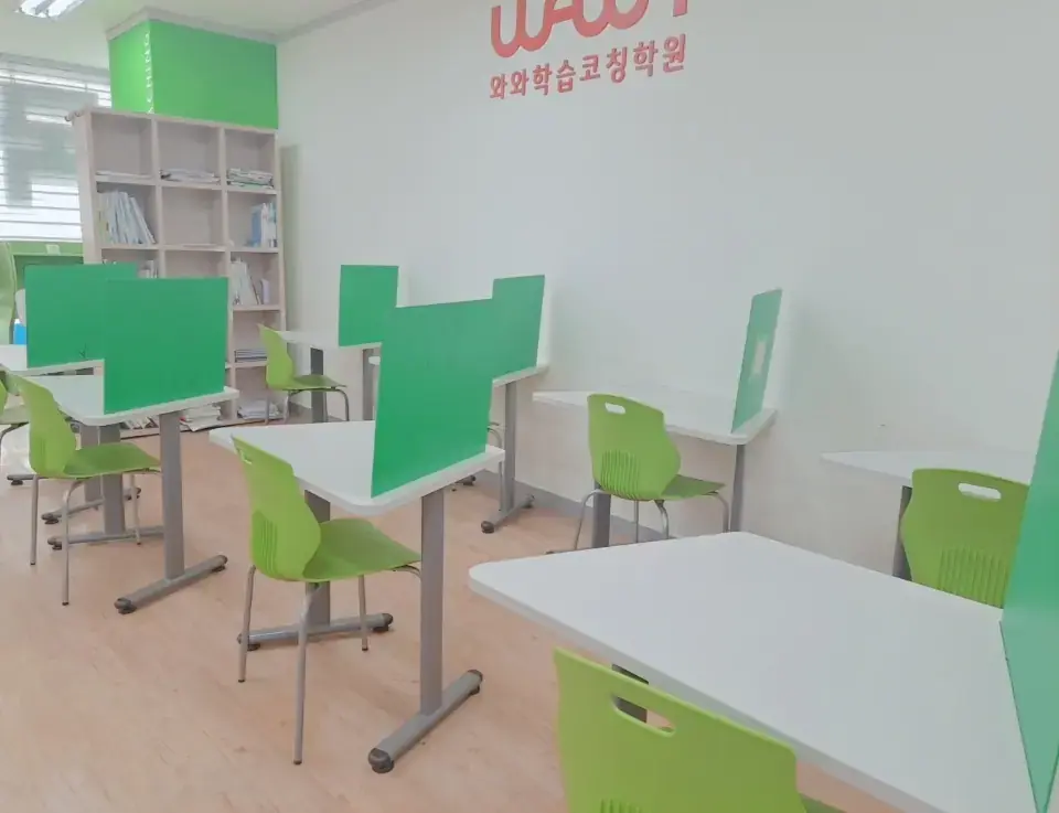 원목 책장 옆으로 초록 칸막이 책상과 연두색 의자가 줄지어 놓인 은평점 밝은 학습실