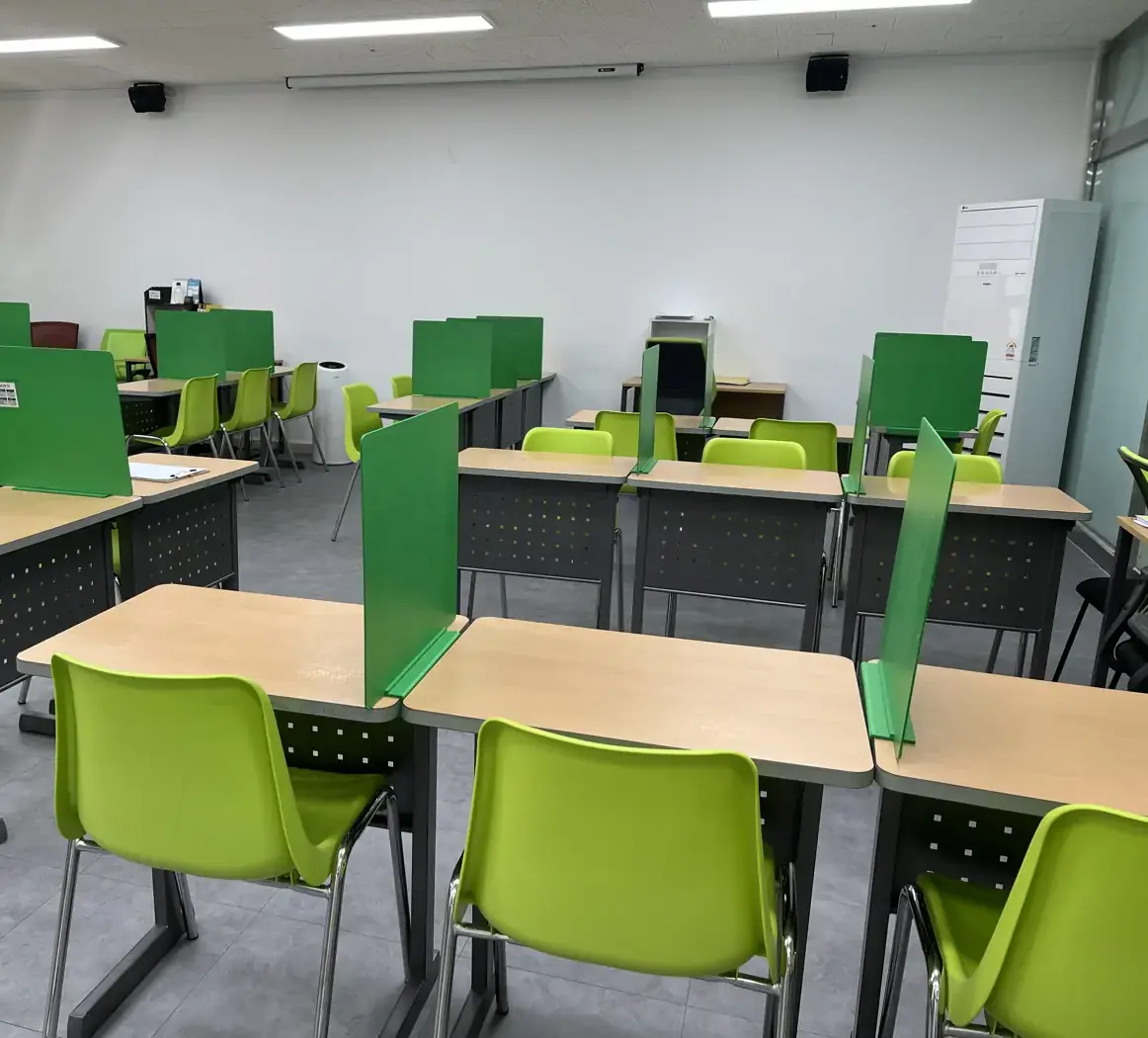 흰 벽과 스탠드 에어컨을 향해 초록 가림판 책상이 정렬된 다산지금점 교실