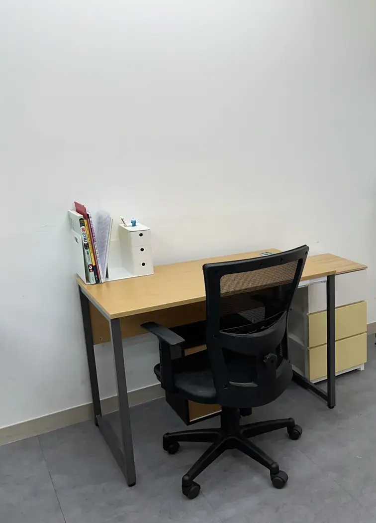 흰 벽 앞에 원목 책상과 메시 의자가 놓인 다산지금점 개별 지도 공간